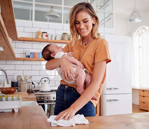 mother with baby in arm cleaning countertop